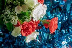 Bouquet of red and white artificial flowers on blue background. Selective focus photo