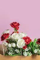 artificial flowers in a paper bag on a pink background. place for text. photo