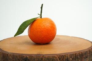 Single fresh orange fruit with water drop on round tray wood isolated on white background photo