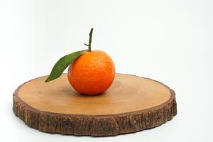 Single fresh orange fruit with water drop on round tray wood isolated on white background photo