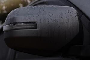 Close up of car rear view mirror with water drops on it. Transportation background of cover mirror wing of grey car. Folding side mirror. photo