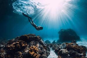mujer apneísta con aletas submarino. buceo libre y hermosa ligero en Oceano foto
