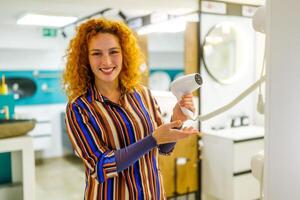 Portrait of buyer in bathroom store. Redhead woman is choosing equipment for her bathroom. photo