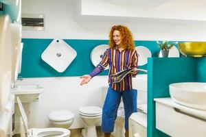 Portrait of salesperson in bathroom store. Happy redhead woman works in bath store. Sales occupation. photo