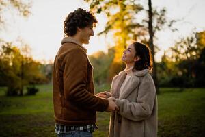 Portrait of happy loving couple in park in sunset. Couple in silhouette looking at each other. photo