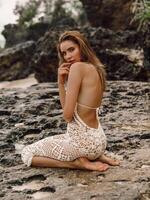 Beautiful young woman in dress posing at tropical beach photo