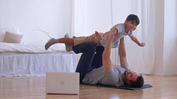 Familie Fitness beim heim, Vater Coach, Sport Kind, Spaß Gymnastik. glücklich Vater und Sohn tun Morgen Gymnastik beim Zuhause mit Laptop video