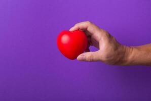Hand with red heart on purple background. photo