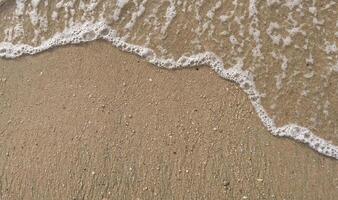 White bubble of Sea wave on fine sand at the beach photo