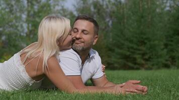 Loving happy couple man and woman lie on the grass touching their noses to each other video