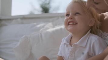 portrait de une peu attrayant garçon souriant magnifiquement tandis que séance suivant à maman video