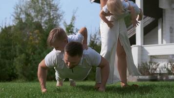 Young family mom dad and two sons do morning exercises on the grass near the house. Sport family. Close-up video