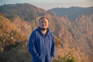 asiático grasa hombre con hermosa amanecer de Khao san nok guau montaña kanchanaburi.khao san nok guau es el más alto montaña en Khao laem nacional parque. eso es 1767 metros encima mar nivel. foto