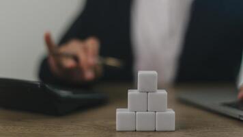 Businesswomen stack blank wooden cubes on the table with copy space, empty wooden cubes for input wording, and an infographic icon photo