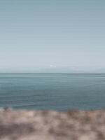 Looking out to a distant snowy mountain peak across the ocean photo