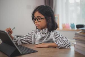 linda asiático pequeño niña niños utilizando un ordenador portátil computadora, estudiando mediante un en línea e-learning sistema. foto