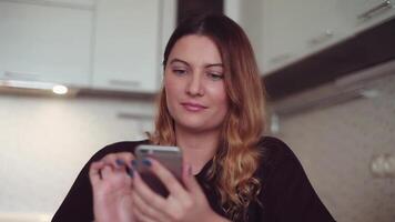 bellissimo giovane ragazza con lungo capelli è fabbricazione un' chiamata per sua amico utilizzando un' smartphone a casa e sorridente. bene umore. Sorridi. dispositivi. video