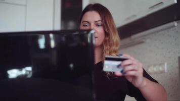 en skön ung kvinna med lång hår går in kreditera kort data in i ett uppkopplad Lagra använder sig av en mobil dator video