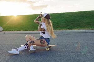 retrato de un hipster joven niña sonriente con un longboard a puesta de sol. foto