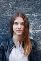 Young beautiful woman in dress and leather jacket standing at roof near fence photo