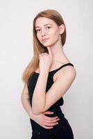 Fashion young woman smiles, confused looking at the camera on a gray background photo