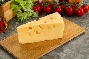 Swiss Maasdam cheese triangle over board photo