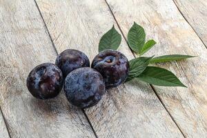 Raw purple plums heap with leaves photo