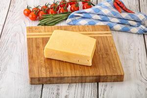 Piece of natural organic cheese over board photo