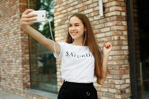 Charming young lady is making selfie on a camera photo