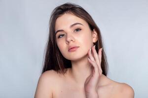 Beautiful Young Woman with Clean Fresh Skin touch own face . photo