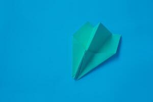 amarillo origami avión en un azul antecedentes. foto