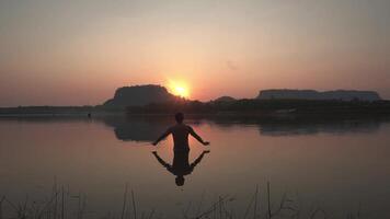 een jong Mens beoefenen geestelijk yoga in voorkant van de berg Bij de zon, zonsopkomst Gezondheid. video