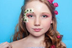 Positive girl. Little girl with daisies in her hands on a blue background. photo