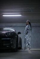 Girl with perfect body in silver suit near car, fashion shoot photo
