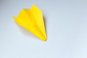 amarillo origami avión en un blanco antecedentes. foto