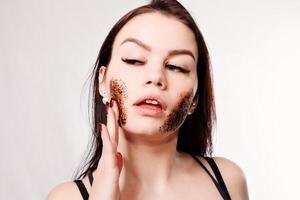 Brunette cleanses the skin with coffee scrub photo