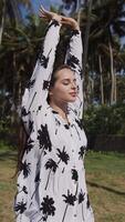 jung Brünette Mädchen auf das Hintergrund von Palme Bäume im ein Kleid. video