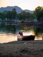 Boat drifts peacefully on serene river beneath golden sunset photo