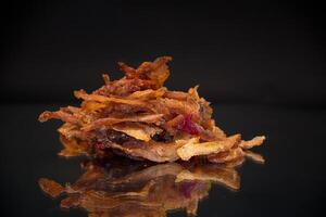 handful of dried meat marinated with spices, isolated on a black background. photo