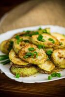 fried zucchini in circles with fresh herbs in a plate photo