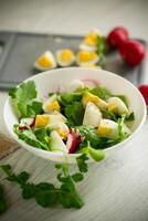 Fresh spring salad with fresh lettuce leaves, radishes, boiled eggs in a bowl photo