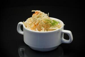 sauerkraut with carrots and spices in a white bowl photo