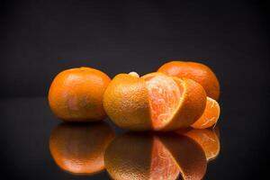 ripe tangerines with peel on black background photo