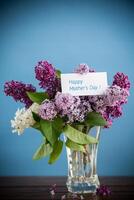 bouquet of different blooming spring lilacs in a vase on blue background photo