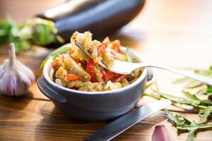 berenjena frito salteado con otro vegetales en un plato foto