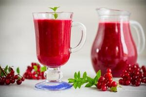 recién exprimido grueso natural jugo con pulpa desde maduro rojo viburnum en un licorera foto