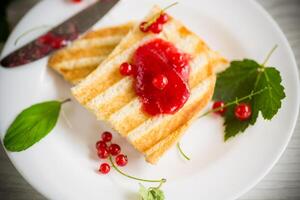 fried bread croutons for breakfast with redcurrant jam in a plate with berries photo