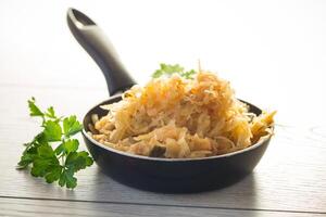 cabbage stewed with spices and carrots in a frying pan , photo