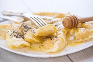 sweet cooked dumplings with cottage cheese, poppy seeds and honey. photo