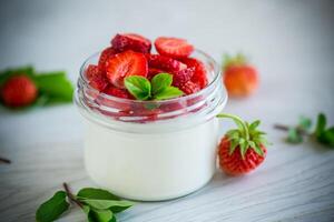 Sweet homemade yogurt with fresh ripe strawberries in a glass jar photo